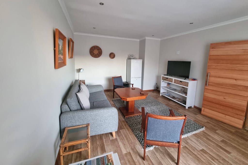Helles Wohnzimmer mit Sofa, Couchtisch, Teppich und Fernseher, aufgenommen aus der Raumecke.