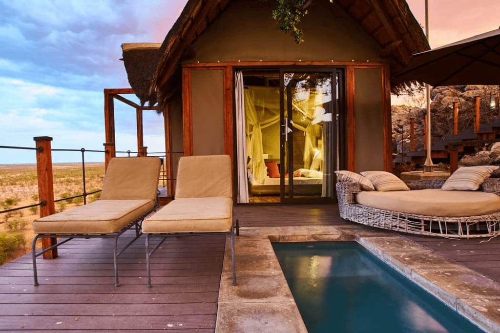 Terrasse einer Zelthütte mit Liegen, Rundsofa und kleinem Pool im warmen Abendlicht