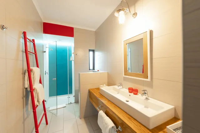Modernes Badezimmer mit Doppelwaschbecken, Glasdusche und roter Handtuchleiter