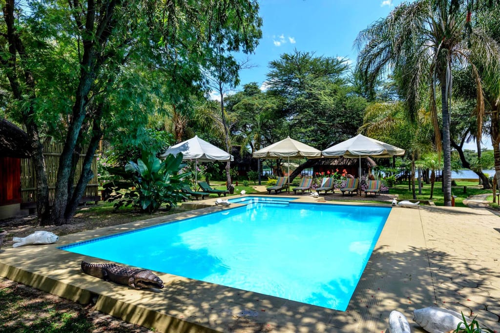 Rechteckiges Schwimmbecken in sonniger Gartenanlage mit Liegen und Sonnenschirmen