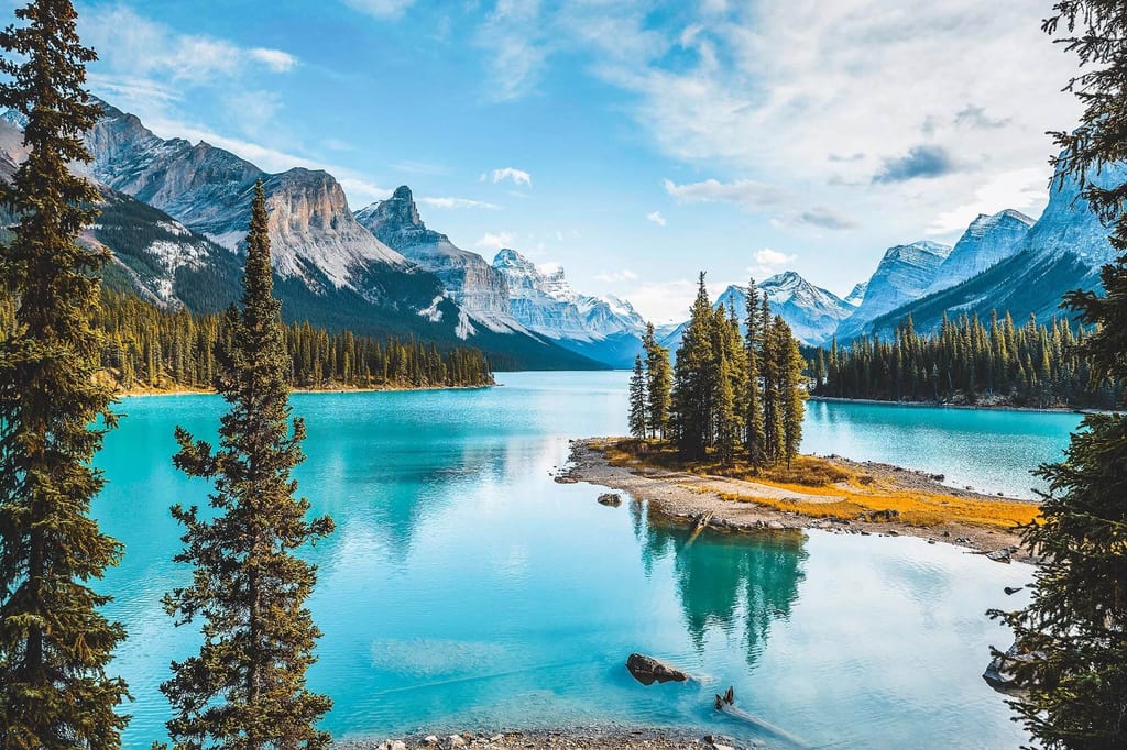 Türkisfarbener Gebirgssee mit kleiner Waldinsel und schroffen Bergen in den Rocky Mountains, Kanada.