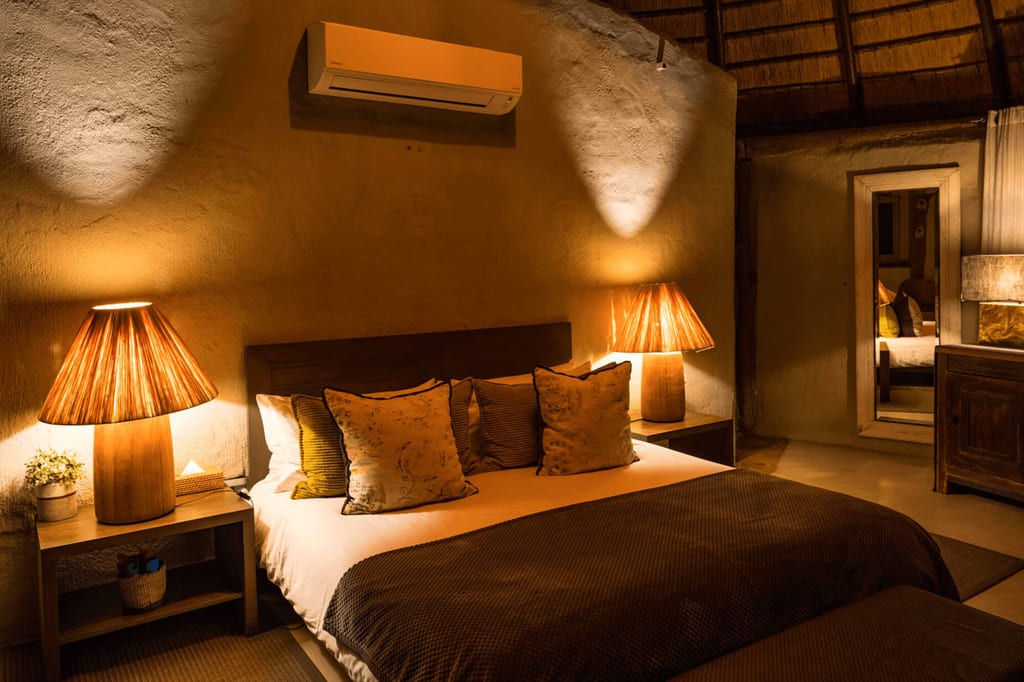 Gemütliches Schlafzimmer mit Doppelbett, warmen Tischlampen und Zierkissen in gedämpftem Abendlicht.