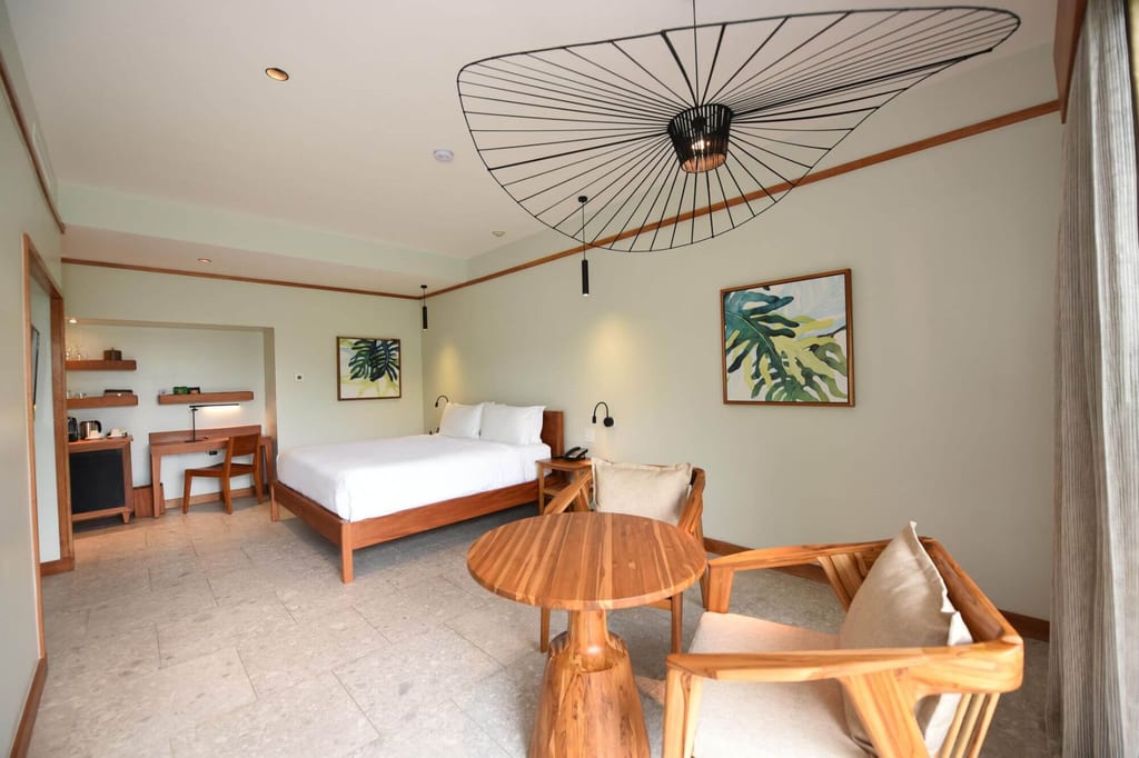 Helles Hotelzimmer mit Doppelbett, Holzmöbeln und Sitzecke bei Tageslicht