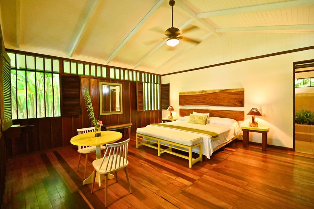 Helles, warmes Schlafzimmer in Holzvilla mit Doppelbett, Holzboden und Deckenventilator