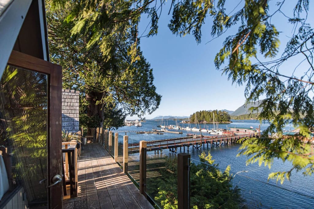 Terrasse am Küstenhaus mit Blick auf Steg, Boote und Insel im warmen späten Nachmittagslicht.