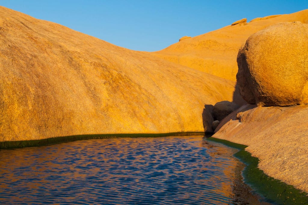 Goldene Felsformationen und kleine Wasserfläche im warmen Seitenlicht, klare Stimmung