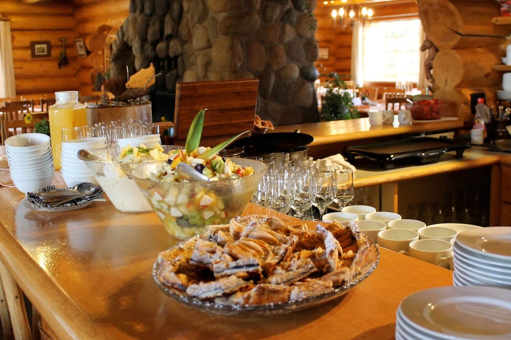 Buffet mit Obstsalat, Müsli und Gebäck auf einer Holztheke in gemütlichem Gastraum
