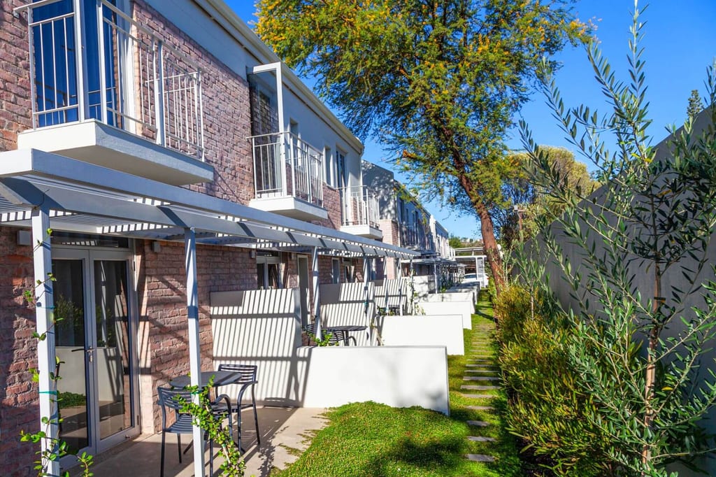 Reihenhäuser mit Terrassen und Gartenweg bei sonnigem, klarem Tageslicht
