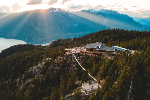 Luftaufnahme: Bergrestaurant mit Aussichtsplattformen und Sonnenstrahlen über Gebirge und See