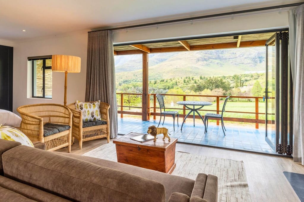 Helles Wohnzimmer mit offener Falttür zur Terrasse und Blick auf grüne Hügel.
