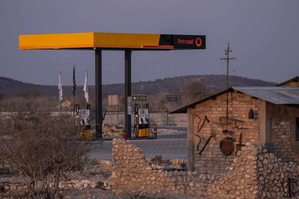 Petrosol-Tankstelle in trockener Buschlandschaft bei Abendlicht, Vordergrund Steinmauer und rustikales Gebäude