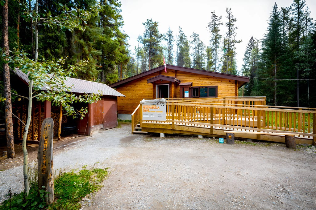 Holzhaus mit Rampe vor Nadelwald an einem bewölkten Tag, ruhige Außenansicht