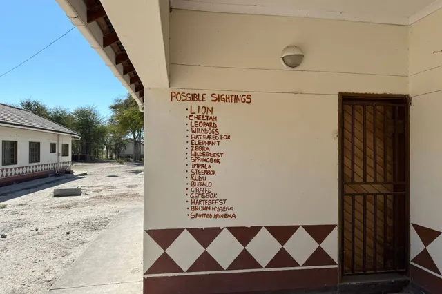 Gebäudeecke mit aufgemalter Liste 'Possible Sightings' an der Wand bei sonnigem Tageslicht.