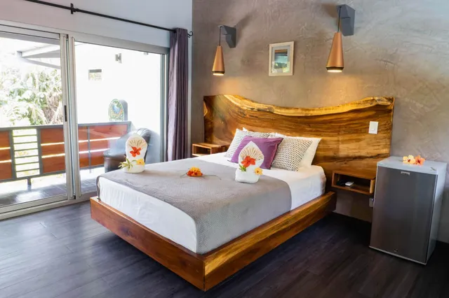 Modernes Hotelzimmer mit Holzbett, dekorierten Handtüchern und Balkontür bei Tageslicht