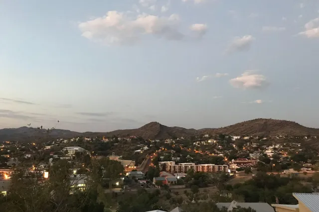Abendlicher Panoramablick auf eine Kleinstadt im Binnenhochland Namibias mit Hügeln und Straßenlichtern