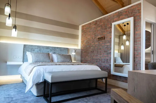 Modernes, gemütliches Hotelzimmer mit Doppelbett, Ziegelwand und großem Wandspiegel