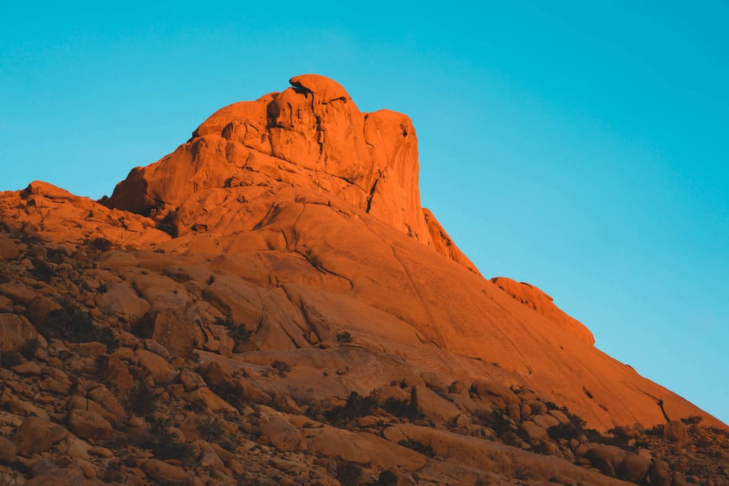 Roter Felsen im warmen Seitenlicht vor klarem blauem Himmel