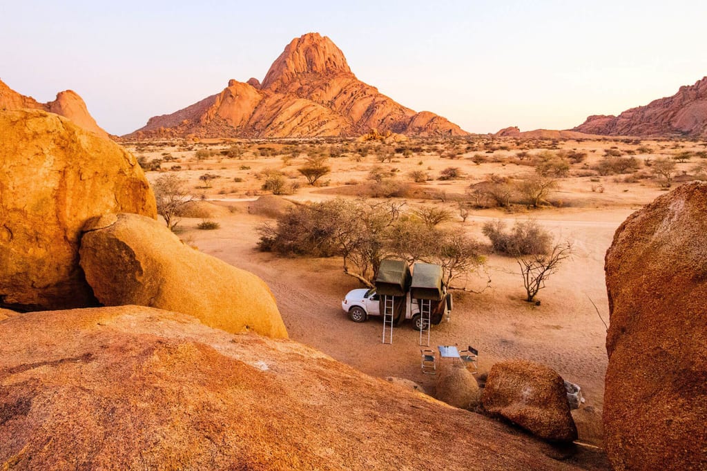 Camping mit Dachzelten vor der markanten Spitzkoppe in Namibia bei warmem Abendlicht
