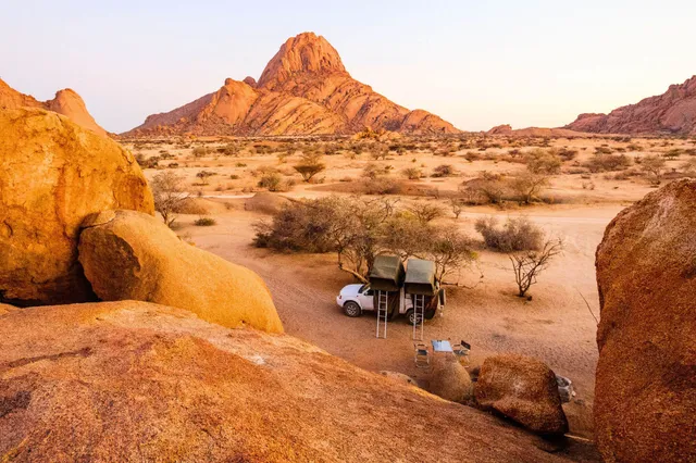 Camping mit Dachzelten vor der markanten Spitzkoppe in Namibia bei warmem Abendlicht