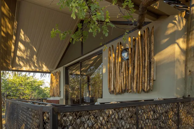 Außenbalkon einer Lodge mit Holzverkleidung und Gabionen im warmen Spätnachmittagslicht.