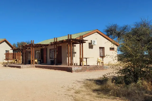 Einschossige Bungalows mit Terrassen in trockener Buschlandschaft bei klarem Mittagslicht