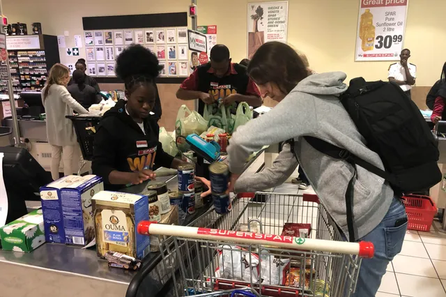 Kundin und Kassiererin an einer Supermarktkasse beim Einräumen und Scannen von Lebensmitteln