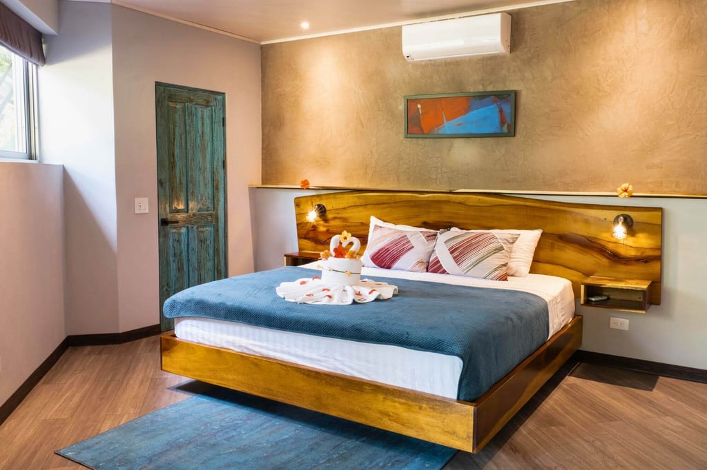 Modernes Doppelzimmer mit Holzbett, blauem Überwurf und dekorativ gefalteten Handtüchern
