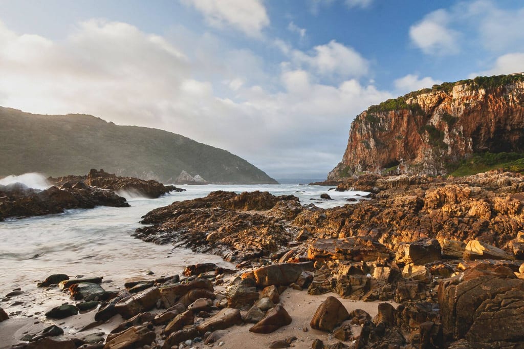 Felsige Küste und Klippen in einer Meeresbucht bei Knysna im warmen Seitenlicht.