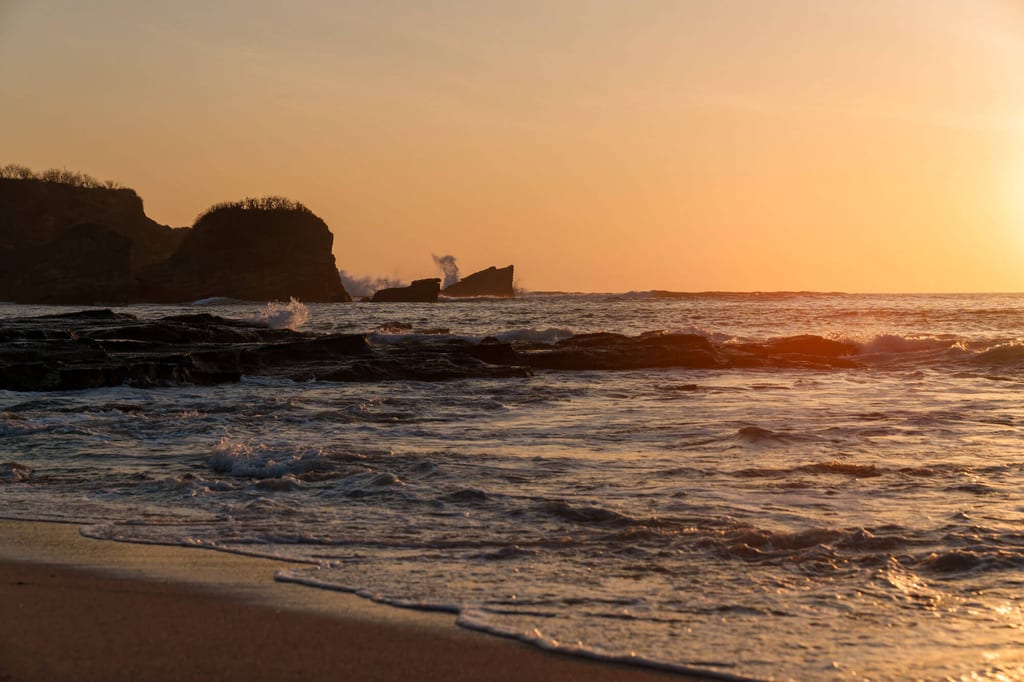 Küstenbild in Costa Rica mit Felsen und Brandung im warmen Licht des Sonnenuntergangs