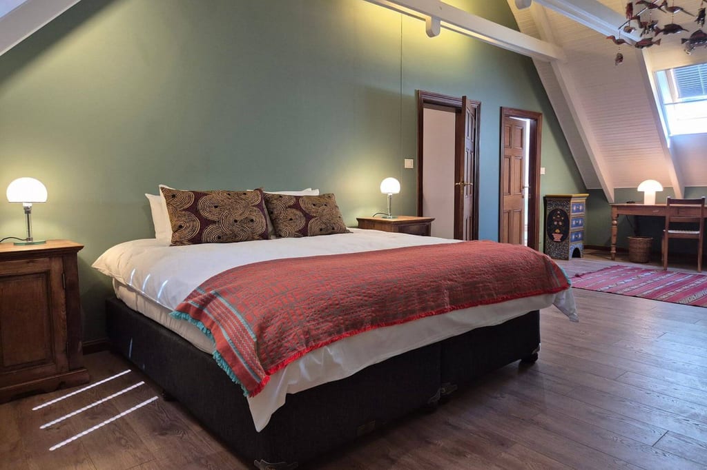 Gemütliches Schlafzimmer mit Doppelbett, grüner Wand, Schreibtisch und warmem Licht