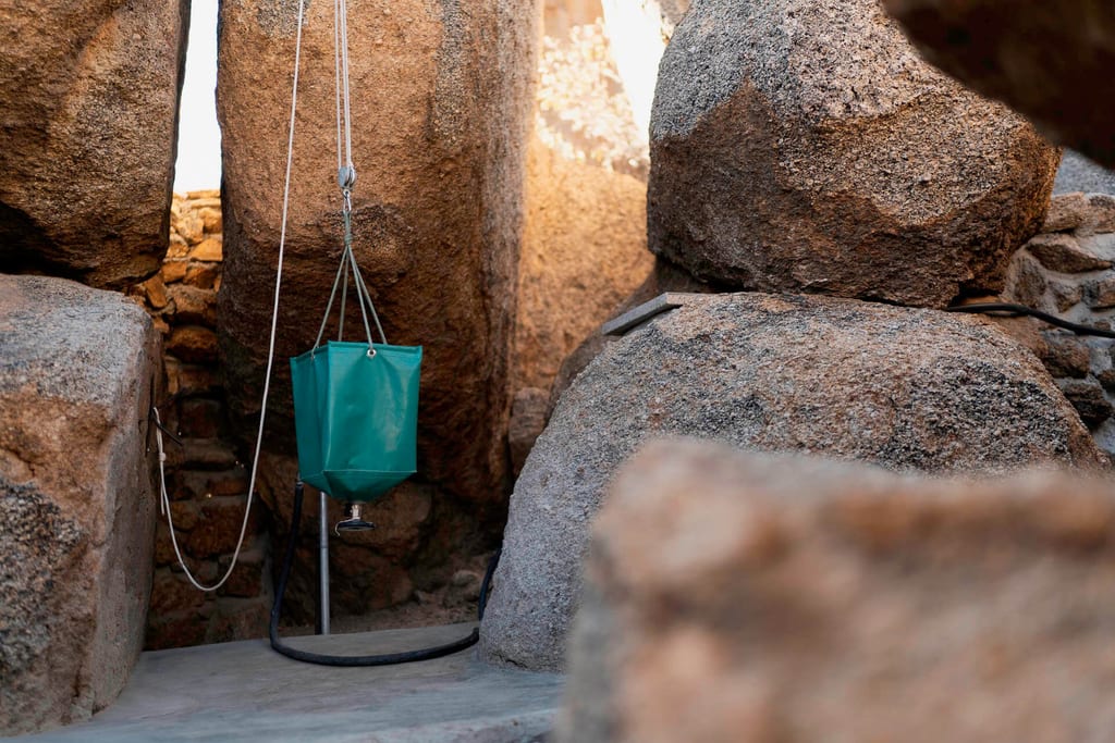 Grüner aufgehängter Wassersack zwischen großen Granitfelsen in warmem Nachmittagslicht.