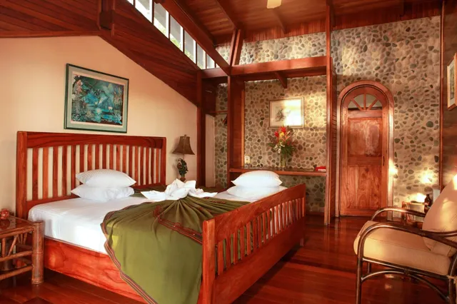 Gemütliches Schlafzimmer mit Holzbetten, Steinwand und warmer Innenbeleuchtung.