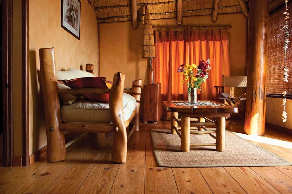 Rustikales Wohnzimmer mit Holzmöbeln, Kaffeetisch und Vase mit Blumen in warmem Licht.