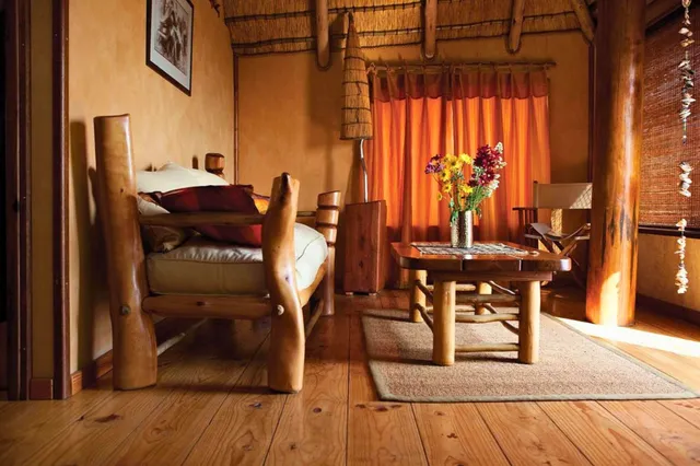Rustikales Wohnzimmer mit Holzmöbeln, Kaffeetisch und Vase mit Blumen in warmem Licht.