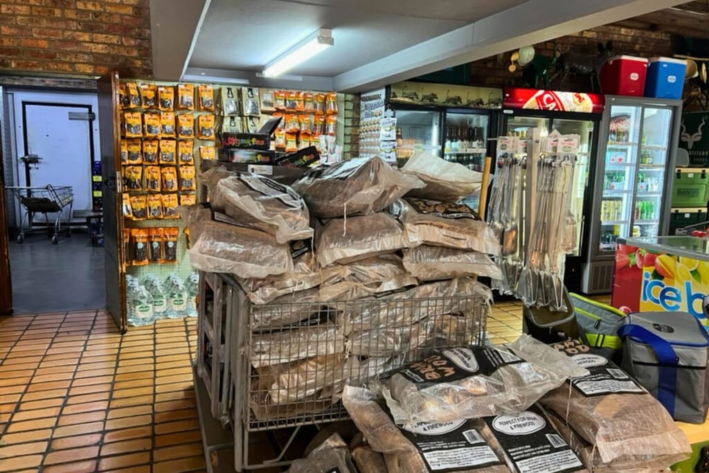 Innenaufnahme eines Ladens mit gestapelten verpackten Säcken in Drahtkörben und Kühlregalen im Hintergrund.