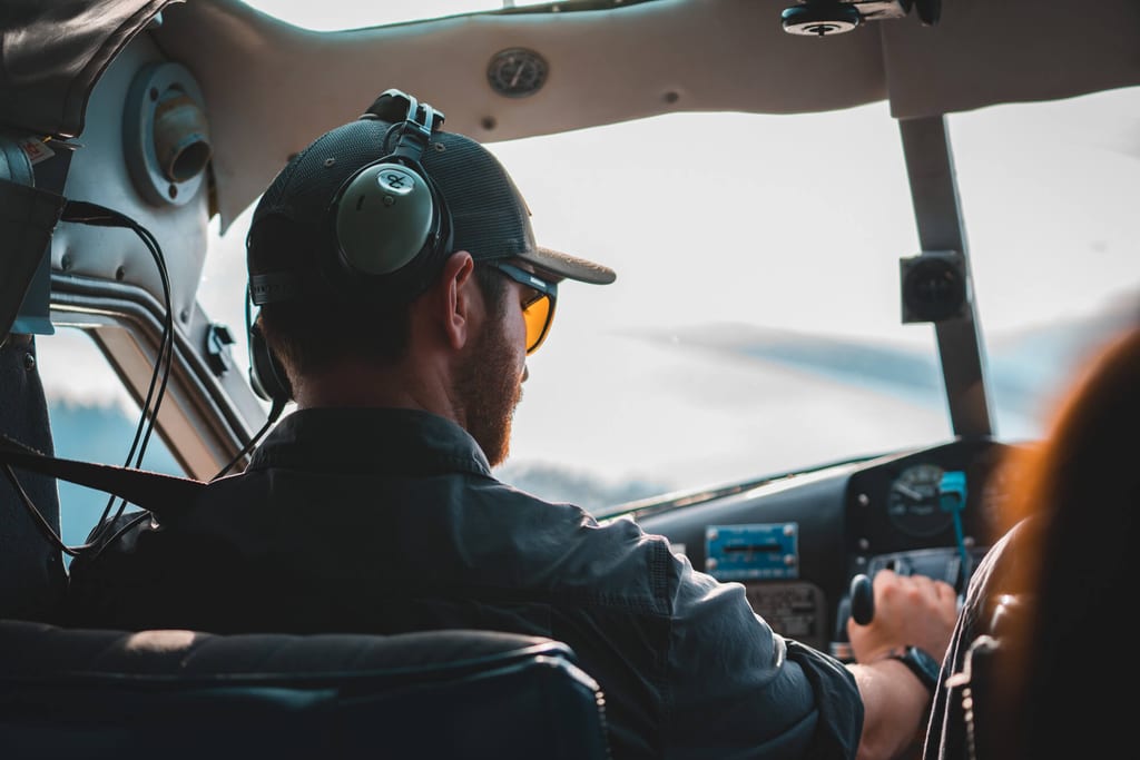 Rückansicht eines Piloten im Cockpit eines Kleinflugzeugs bei Tageslicht.