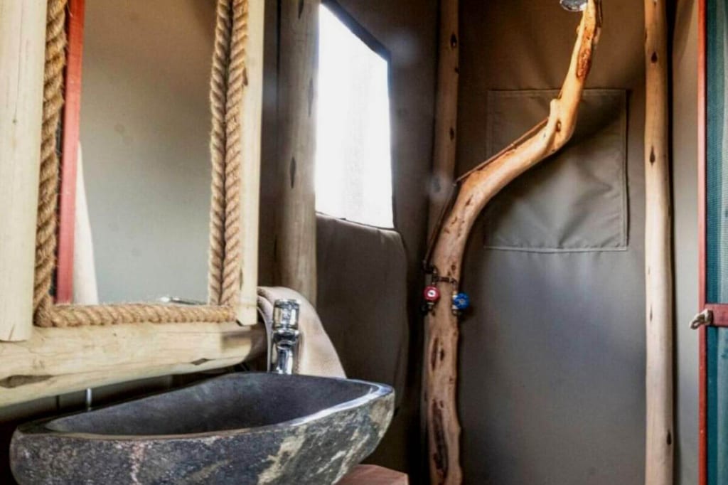 Rustikales Badezimmer mit Steinwaschbecken, Holzspiegel und Duschstange aus naturbelassenem Holz