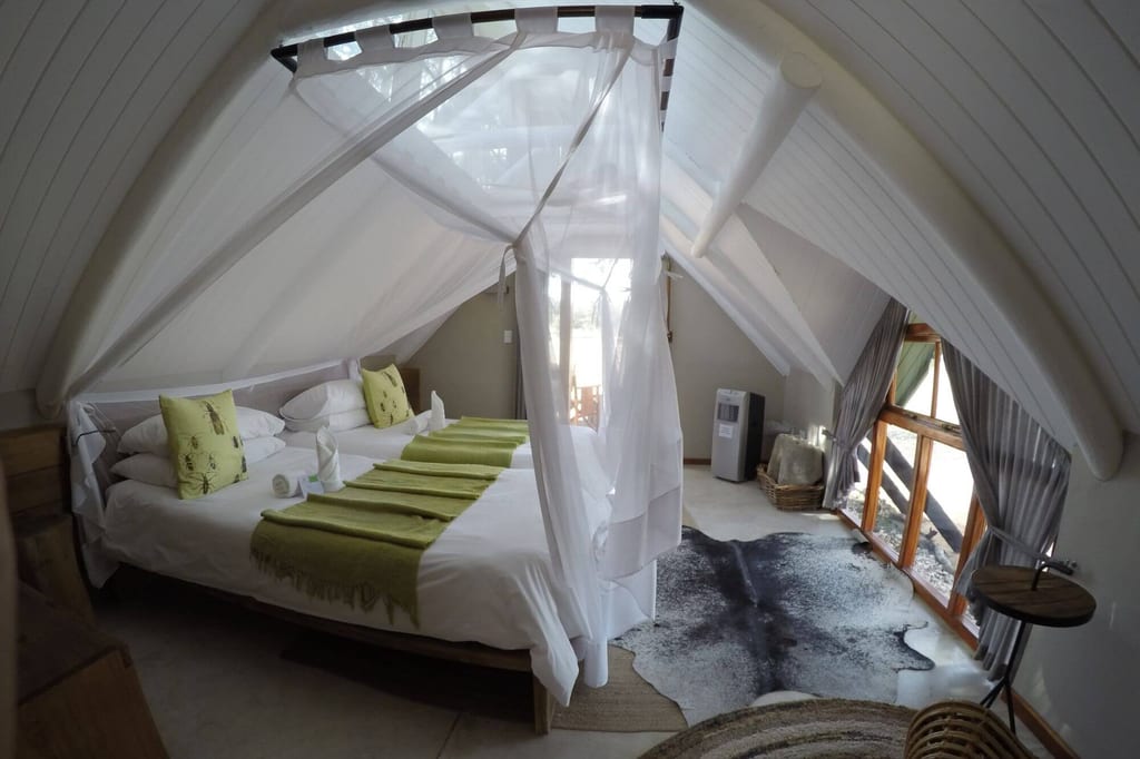 Helles Dachzimmer mit Himmelbett, Moskitonetz und großem Fenster, gemütlich und ruhig beleuchtet.