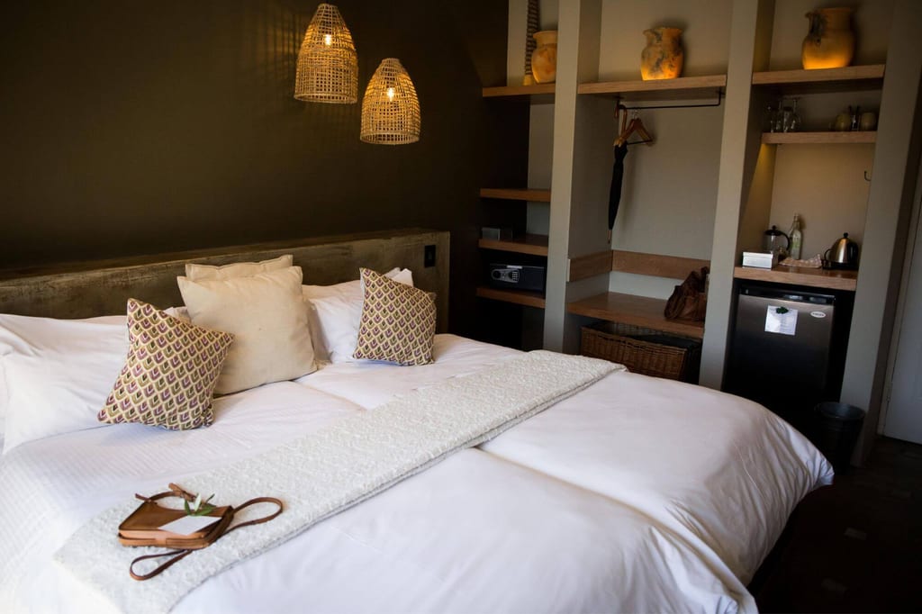 Gemütliches Hotelzimmer mit großem Bett, Kissen und warmen Hängeleuchten.