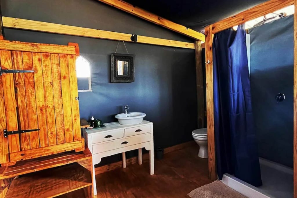 Rustikales Badezimmer mit Holzschrank, weißem Waschtisch und Dusche mit blauem Vorhang.