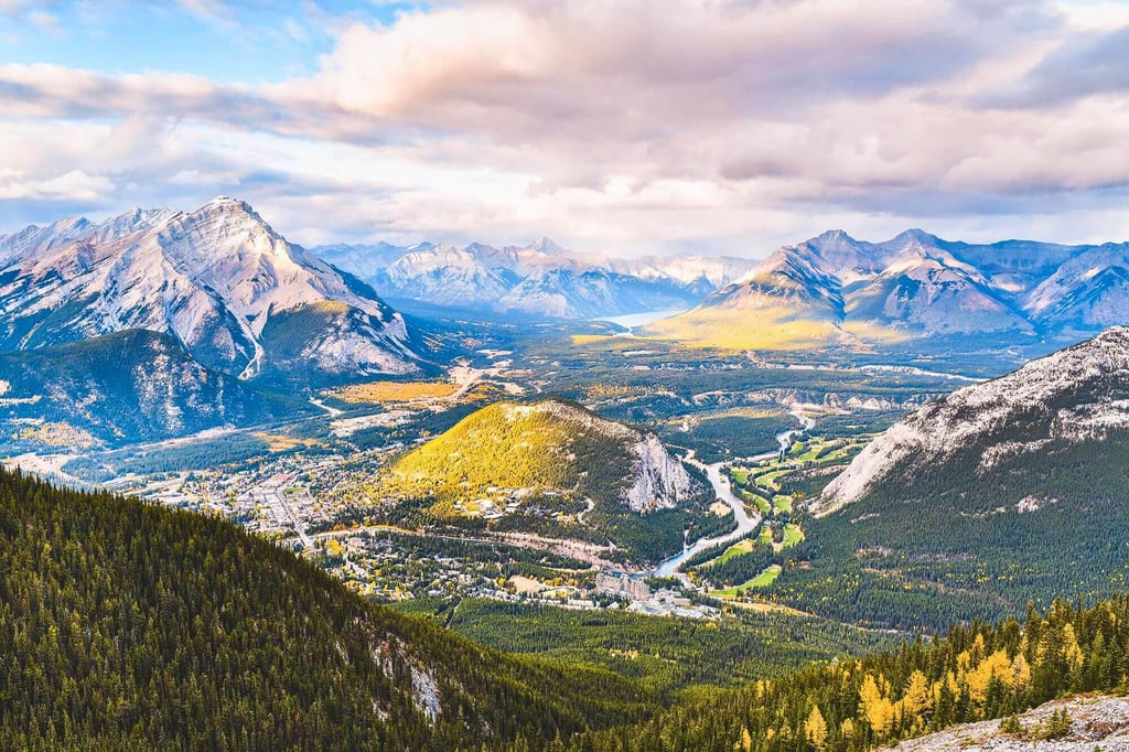 Panorama des Banff-Tals mit Fluss, Wald und Bergen im warmen Spätnachmittagslicht.