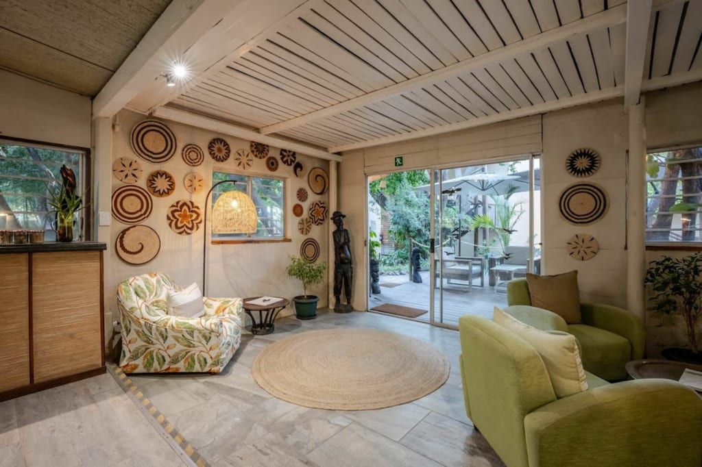 Gemütliche Lounge mit grünen Sesseln, Flechtwanddekorationen und geöffneter Schiebetür zur Terrasse