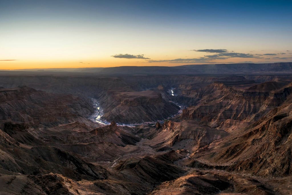 Weite Canyonlandschaft mit schmalem Fluss im Tal bei Dämmerung aus erhöhter Perspektive