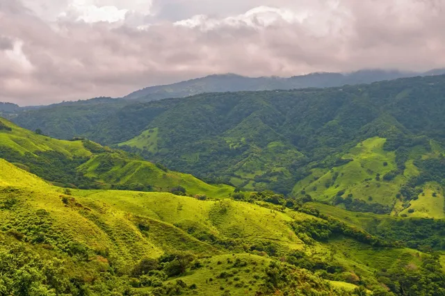 Panoramasicht auf grüne Hügel und Täler im zentralen Hochland von Costa Rica unter bewölktem Himmel.