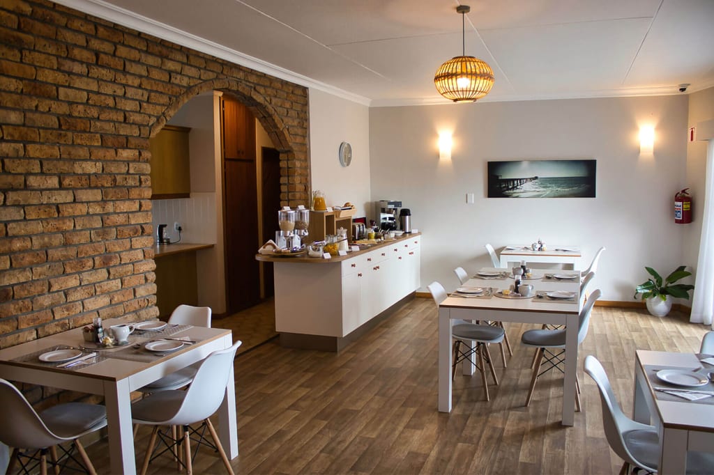 Heller, gemütlicher Frühstücksraum mit gedeckten Tischen, Backsteinbogen und Sideboard mit Kaffee