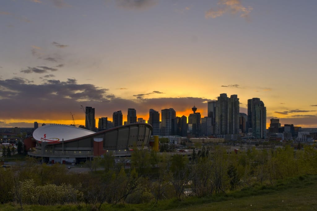 Skyline mit Stadion und Bäumen bei Sonnenuntergang, warme Abendstimmung