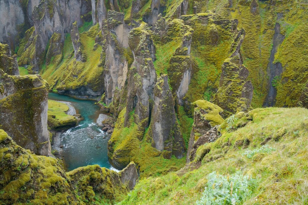 Aussicht auf moosbedeckte Felswände und einen türkisfarbenen Fluss in einer engen Schlucht