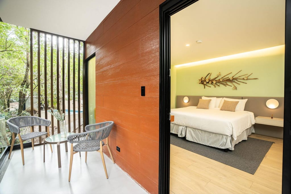 Moderner Lodge-Balkon mit zwei Stühlen und Blick in ein helles Schlafzimmer mit Doppelbett