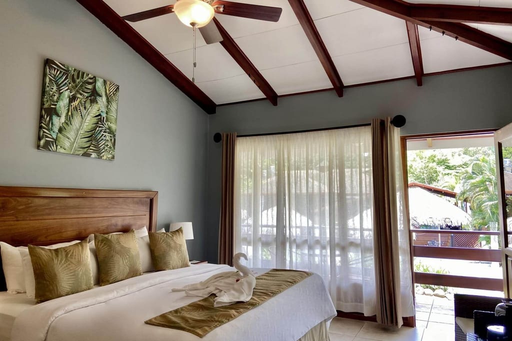 Helles Hotelzimmer mit Doppelbett, Balkonblick und tropischer Dekoration