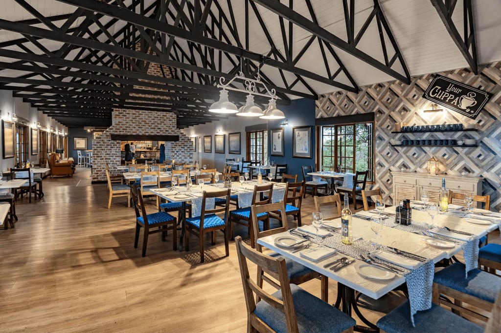 Innenansicht eines gemütlich beleuchteten Restaurants mit eingedeckten Tischen und sichtbaren Deckenbalken.